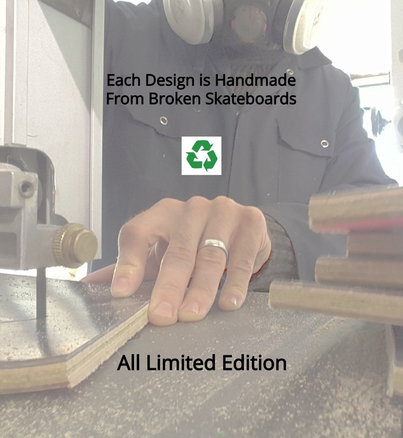 May include: A person's hand is shown cutting a piece of wood with a saw. The wood is light brown and has a green recycling symbol on it. The text "Each Design is Handmade From Broken Skateboards" and "All Limited Edition" is visible in the image.