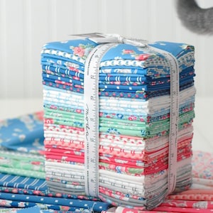 May include: A collection of fabric bundles in floral and patterned designs, secured with a white ribbon. The fabrics display shades of blue, pink, green, and white. A measuring tape is wrapped around the stack. The fabrics are for sewing and quilting.
