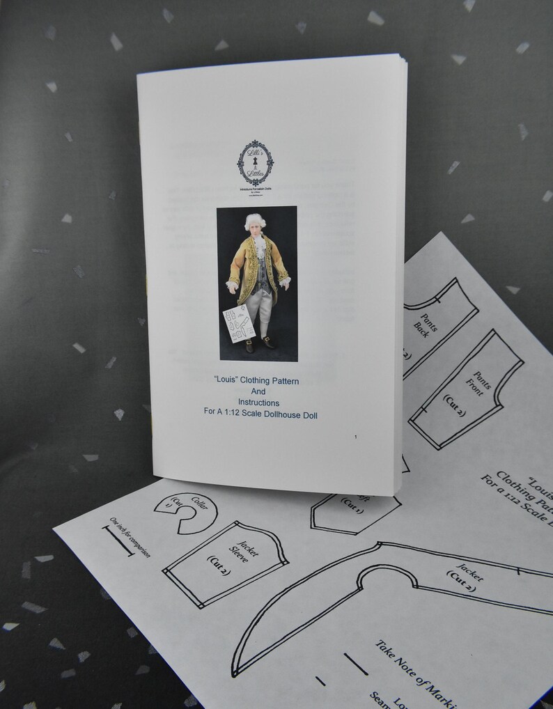 May include: A white booklet titled Louis Clothing Pattern and Instructions for a 1:12 Scale Dollhouse Doll, featuring a photo of a doll in a gold coat. Below it, a paper sheet shows black line drawings of pattern pieces with a one-inch scale bar.