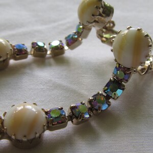 May include: A pair of clip-on earrings with iridescent rhinestones and white shell-like cabochons.
