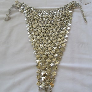 Puede incluir: Un collar de malla de plata con un diseño delicado e intrincado. El collar está hecho de pequeños anillos de metal interconectados que crean un efecto fluido y en cascada.