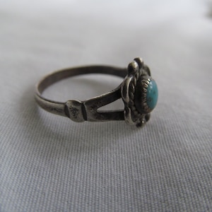 May include: A silver ring with a turquoise stone set in a floral design.
