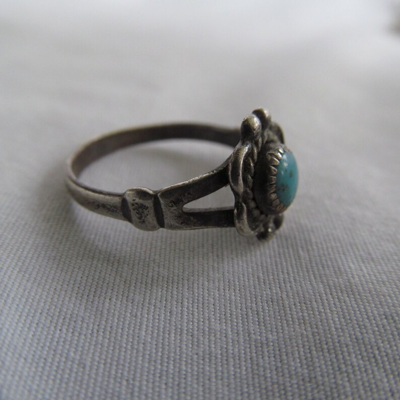 May include: A silver ring with a turquoise stone set in a floral design.