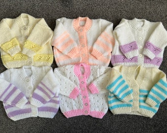 May include: Six knitted baby cardigans in a variety of colours and patterns, including yellow, pink, white, and blue stripes. The cardigans are all made with a soft, comfortable yarn and have a classic button-up design.