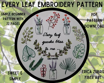 May include: A white embroidery hoop with a black border, featuring a variety of green leaves, flowers, and a quote: "Every leaf speaks bliss to me... Emily Bronte". The hoop is surrounded by a green leafy background.