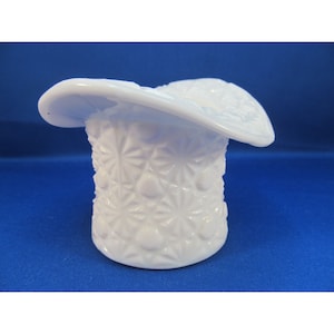 May include: A white milk glass hat shaped vase with a textured design.
