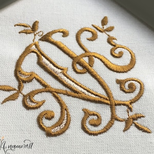 May include: Gold embroidered letter N with a decorative flourish. The embroidery is on a white fabric background.