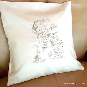 May include: White pillow with a decorative embroidered letter A with floral accents.