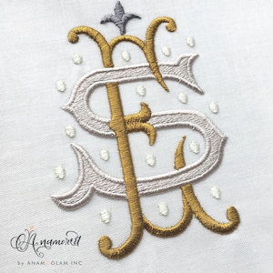 May include: Gold and white embroidered monogram with a decorative flourish at the top. The monogram is surrounded by a dotted pattern.