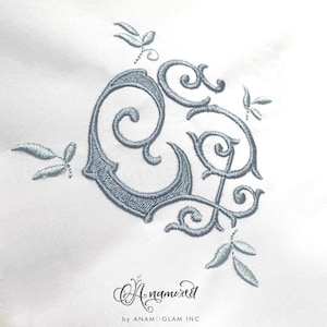 May include: A blue embroidered monogram with a decorative floral design. The monogram is in a script font and the flowers are stylized.