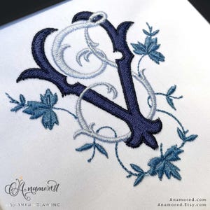 Puede incluir: Monograma bordado con las letras "C" y "V" en azul oscuro y azul claro, con detalles florales. El diseño está sobre un fondo blanco. El nombre de la tienda Etsy "Anamored" es visible.