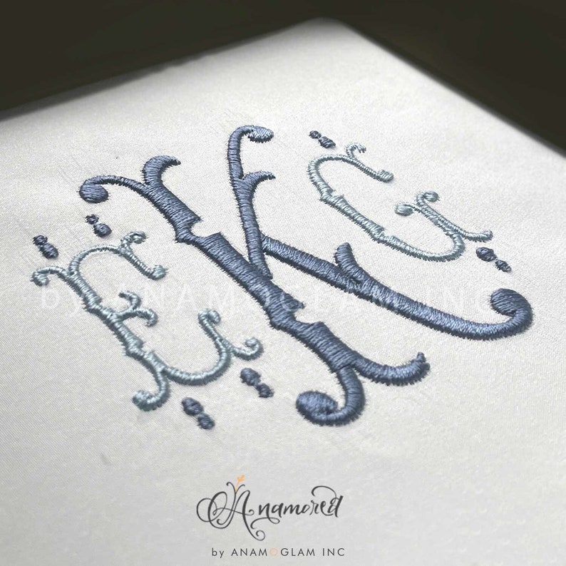 May include: A monogram of the letter "K" in a decorative script font, embroidered in blue and light blue thread on a white fabric background.