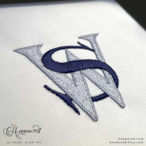 May include: Embroidered monogram featuring the letters "WS" in a stylized design. The letters are in a silver-gray color with a navy blue accent, stitched on a white fabric. The image includes the text "Anamored" and "by ANAM GLAM INC."
