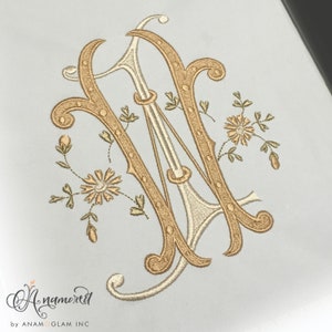 May include: A gold and white embroidered monogram of the letter "W" with floral accents.