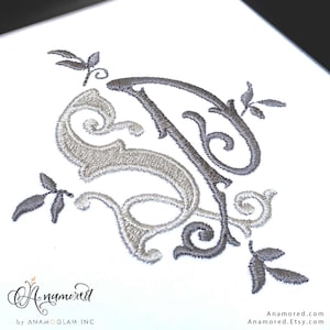 May include: A silver and gray embroidered monogram with a floral design. The monogram is a stylized "S" and "T" intertwined.
