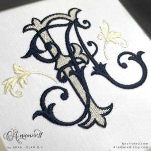 Puede incluir: Monograma bordado en azul marino y beige claro sobre fondo blanco. Las letras entrelazadas presentan detalles florales ornamentados. La imagen incluye el texto "Anamored" y la URL de la tienda Etsy.
