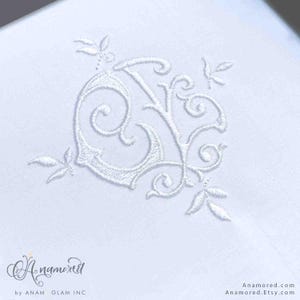 May include: White embroidered monogram with a decorative floral design. The monogram features the letters "J" and "K" intertwined.