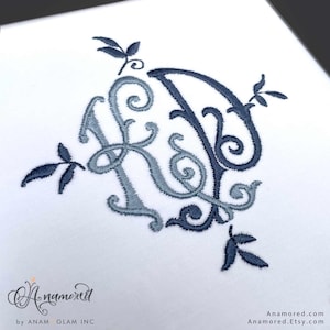 May include: Embroidered monogram featuring the letters "K" and "D" in shades of blue, adorned with floral accents. The design is set against a white background. The image includes the text "Anamored" and "Anamored.Etsy.com".