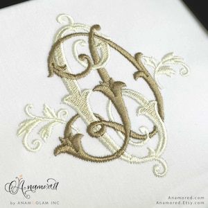 May include: An embroidered monogram in shades of gold and cream, featuring intertwined letters with ornate flourishes and leaf details. The design is centered on a white background, showcasing the intricate stitching and elegant style.
