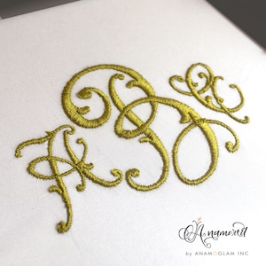 May include: A gold embroidered monogram featuring the letters "AJ" in a decorative script font.