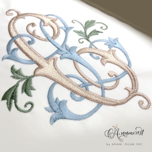 Peut inclure: Un motif de broderie de monogramme représentant la lettre "S" dans une écriture décorative et ornée avec du fil bleu et beige. Le motif comprend des éléments floraux et des volutes.