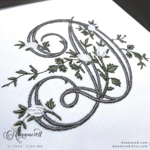 Puede incluir: Monograma bordado con la letra D en forma floral, en gris y blanco. La letra está rodeada de hojas y flores estilizadas.