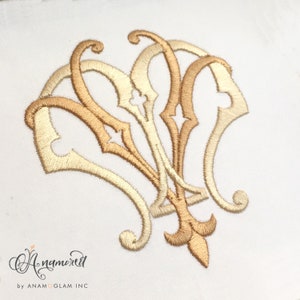 May include: A gold and cream embroidered monogram design with a decorative flourish. The design is in a traditional style and would be perfect for a wedding or other special occasion.