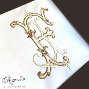 Puede incluir: Un monograma bordado de la letra "F" en oro y blanco con adornos ornamentados. El monograma está sobre un fondo blanco.