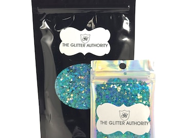 May include: Two resealable bags of teal blue star-shaped glitter. The larger bag is black with the text "The Glitter Authority" printed on a white label. The smaller bag is iridescent and has the same label.