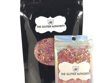 May include: Two resealable bags of pink and gold star-shaped glitter. The larger bag has the text "The Glitter Authority" printed on it. The smaller bag has the same text printed on it.