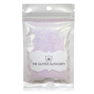 May include: A small white resealable bag filled with iridescent glitter. The bag has a white label with the text "THE GLITTER AUTHORITY" and a logo.