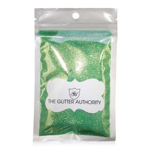May include: A resealable plastic bag filled with green glitter. The bag has a white label with the text "THE GLITTER AUTHORITY" and a logo.
