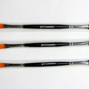 May include: Three black and silver makeup brushes with orange angled tips and black handles. The handles are labeled "Grl Cosmetics".