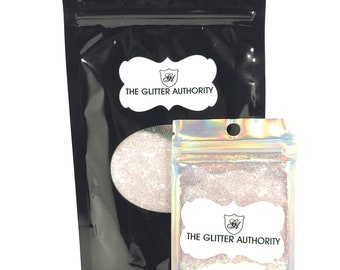 May include: Two resealable bags of iridescent glitter, one larger than the other. Both bags have a white label with the text "THE GLITTER AUTHORITY" and a logo of a shield with the letter "G" inside.