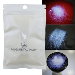 May include: A white resealable bag filled with iridescent white glitter. The bag has a label that reads "The Glitter Authority". The image also shows the glitter on a red surface, a black surface, and in a clear jar.
