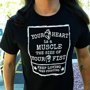 May include: Black t-shirt with a white graphic that says "Your heart is a muscle the size of your fist. Keep loving. Keep fighting."