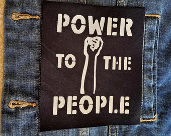 May include: Black patch with white text that reads "POWER TO THE PEOPLE" with a raised fist graphic.