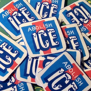 Może przedstawiać: Kolekcja kwadratowych naklejek z napisem "ABOLISH ICE" w białych literach na niebieskim i czerwonym tle. Naklejki są rozrzucone na zielonej powierzchni, z wyraźnie widocznym tekstem.