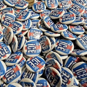 May include: A collection of round buttons with the text "ABOLISH ICE" in white and red on a blue background. The buttons are scattered, showing the design on each button.