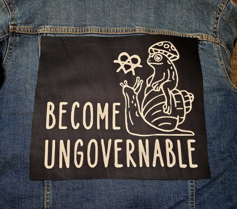May include: A black patch with white text and a graphic of a frog riding a snail. The text reads "Become Ungovernable".