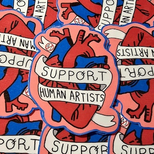 May include: A collection of stickers featuring a stylized anatomical heart design in red and blue, outlined in pink. A white banner across the heart reads "SUPPORT HUMAN ARTISTS". The background is filled with similar stickers.