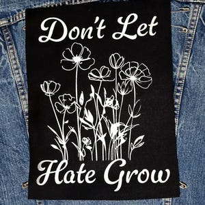 Peut inclure: Écusson thermocollant noir avec du texte blanc et un motif floral. Le texte dit "Ne laissez pas la haine grandir".
