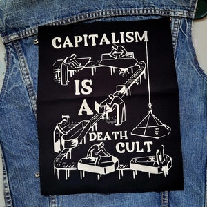 以下が含まれることがあります： 「資本主義は死の教団である」というテキストと、組み立てラインで働く人々のグラフィックが描かれた白黒のパッチ。パッチは青いデニムジャケットに縫い付けられています。