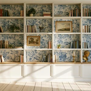 Könnte beinhalten: Ein großes, deckenhohes weißes Bücherregal aus Holz mit fünf vertikalen Abschnitten und einer Rückwand mit blau-weißem Blumenmuster. Die Regale sind mit verschiedenen Büchern, gerahmter Landschaftskunst, kleinen Topfpflanzen und einer goldenen Büste gefüllt.