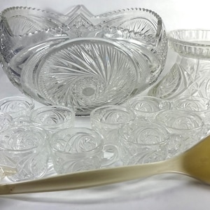 Puede incluir: Un juego de cuenco de ponche de vidrio vintage con un cuenco grande y transparente con un patrón de remolino, 12 tazas a juego, una cuchara y una base separada. El juego está hecho de vidrio transparente con un diseño de vidrio cortado.