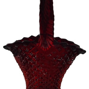 Könnte beinhalten: Ein roter Glaskorb mit einem gedrehten Griff. Der Korb hat ein Diamantenmuster und einen klaren Boden.