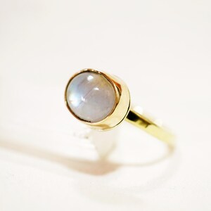 May include: A gold ring with a white moonstone set in the center.