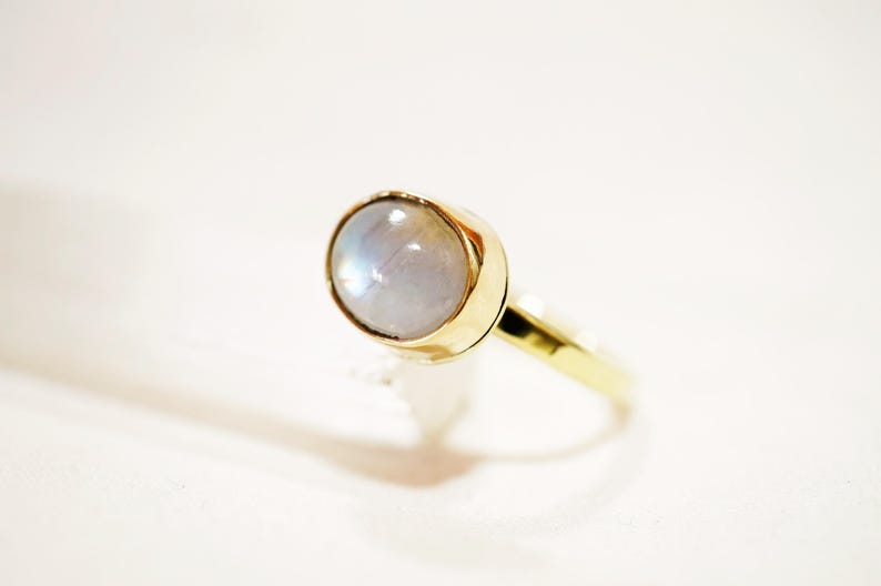 May include: A gold ring with a white moonstone set in the center.