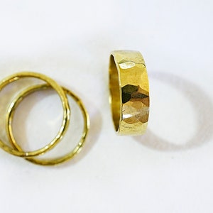 May include: Three gold rings, two are thin and smooth, one is thick and hammered.