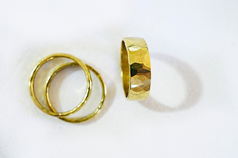 May include: Three gold rings, two are thin and smooth, one is thick and hammered.